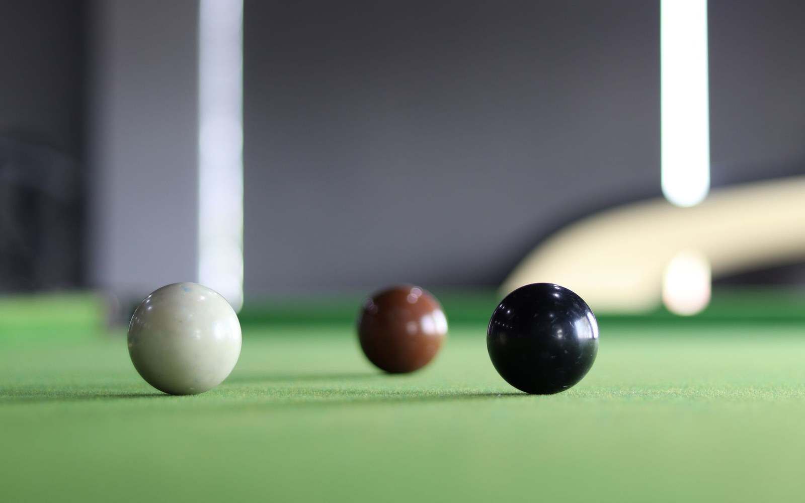 White, brown and black snooker balls resting on a green baize table